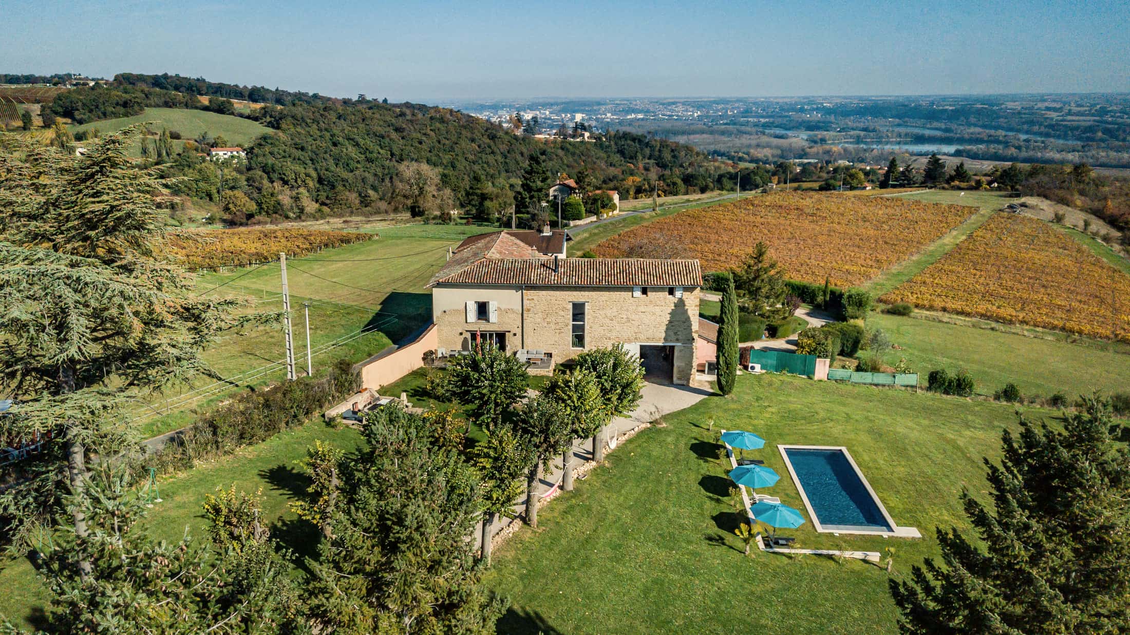 Vue aérienne de la bâtisse en pierres dorées, entourée de vignes, au sud du Beaujolais